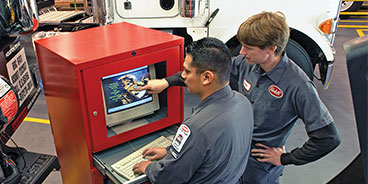 two mechinics examine computer screen